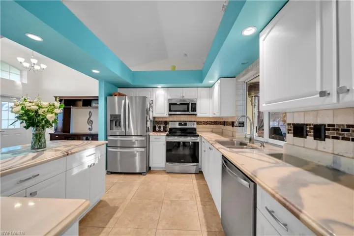 Kitchen featuring white cabinetry, appliances with stainless steel finishes, decorative backsplash, vaulted ceiling, and recessed lighting