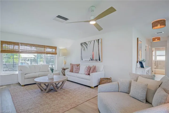 Living room with visible vents, ceiling fan, and light wood-type flooring