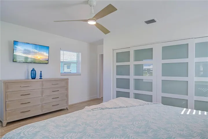 Bedroom featuring light wood finished floors, baseboards, visible vents, and ceiling fan