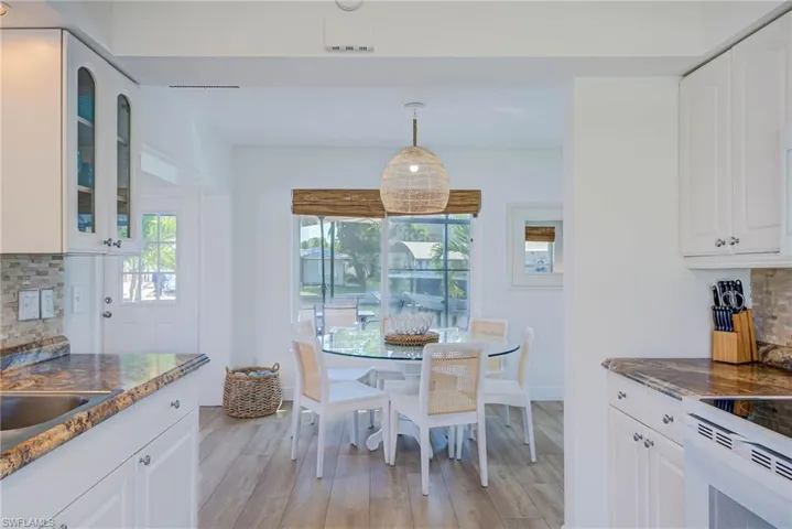 Kitchen featuring glass insert cabinets, tasteful backsplash, light wood-style floors, and white cabinets