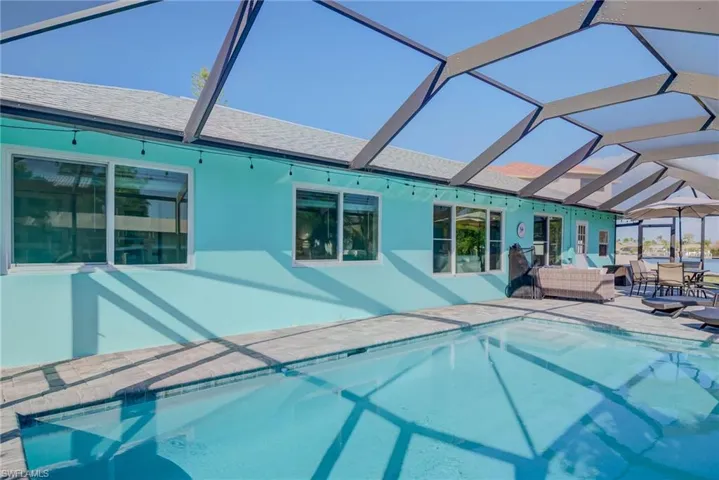 Pool featuring outdoor lounge area, glass enclosure, and a patio area