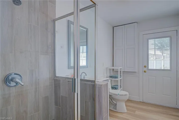 Bathroom with wood finished floors, a stall shower, and toilet