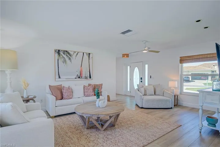 Living room with baseboards, visible vents, a ceiling fan, and wood finished floors