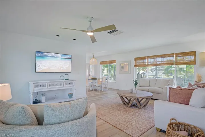 Living area featuring a ceiling fan, visible vents, baseboards, and wood finished floors