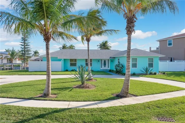 View of front facade featuring a front yard, fence, and curved driveway