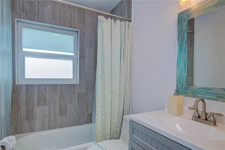 Bathroom with shower / bath combination with curtain, toilet, and vanity