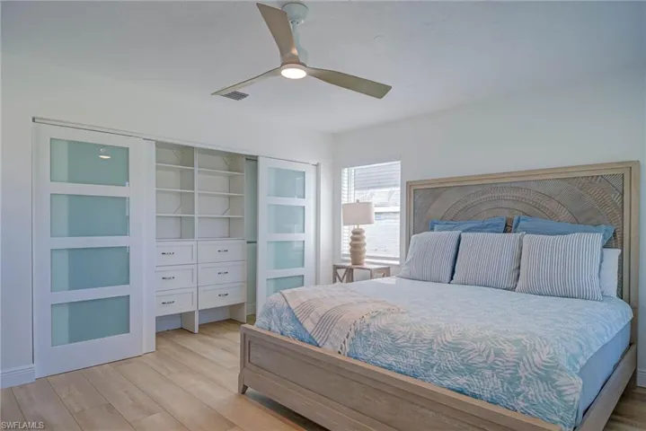 Bedroom with a closet, visible vents, ceiling fan, and wood finished floors