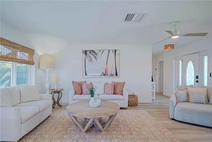 Living room featuring baseboards, a ceiling fan, visible vents, and light wood-type flooring