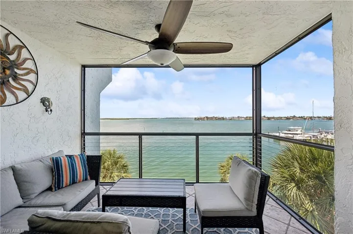 Sunroom with ceiling fan and a water view
