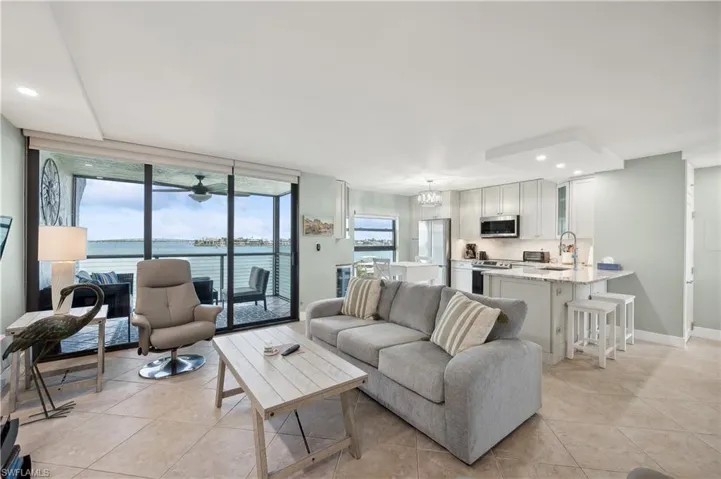 Living room with a water view, light tile flooring, ceiling fan, floor to ceiling windows, and sink