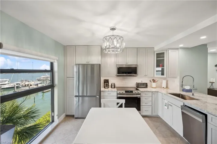 Kitchen with sink, a healthy amount of sunlight, light tile flooring, and appliances with stainless steel finishes