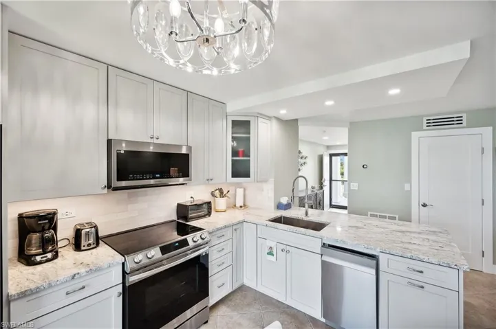 Kitchen featuring appliances with stainless steel finishes, sink, light tile flooring, and kitchen peninsula