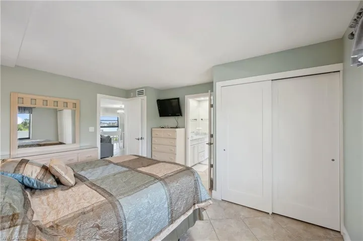 Bedroom featuring a closet, light tile flooring, and ensuite bath