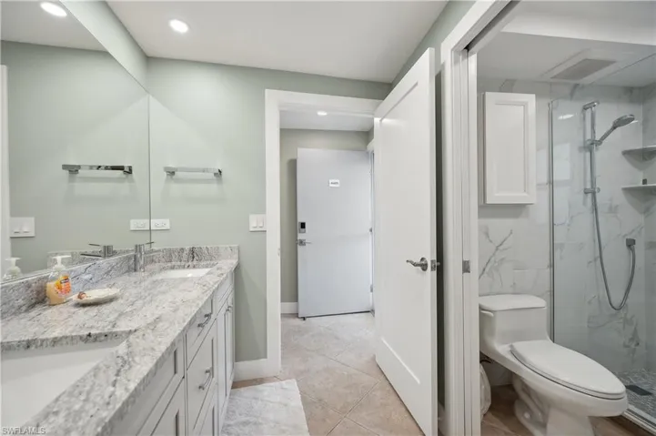 Bathroom featuring tile flooring, an enclosed shower, toilet, and vanity