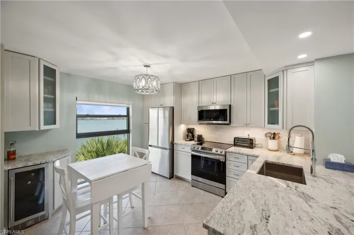 Kitchen featuring an inviting chandelier, beverage cooler, stainless steel appliances, sink, and light tile floors