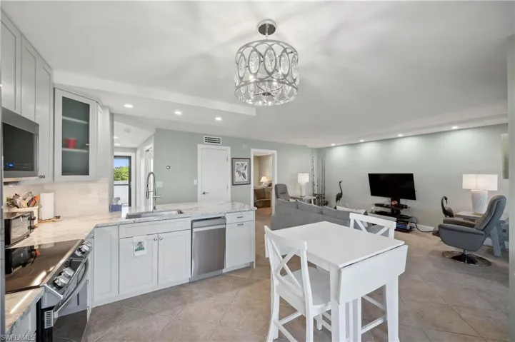 Kitchen with white cabinetry, sink, pendant lighting, and stainless steel appliances