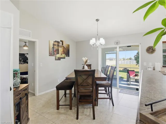 Dining space featuring light tile patterned floors, a chandelier, and vaulted ceiling