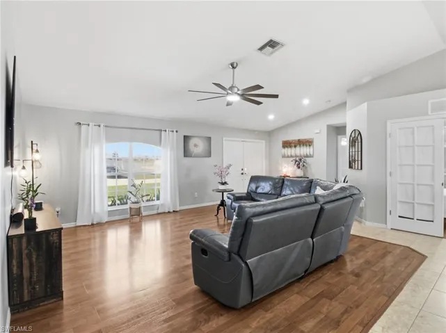 Living area featuring light wood-type flooring, vaulted ceiling, ceiling fan, and recessed lighting and DEN entry door.