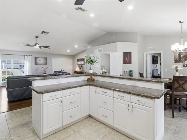 Kitchen featuring open floor plan, white cabinetry, a ceiling fan, pendant lighting, and vaulted ceiling