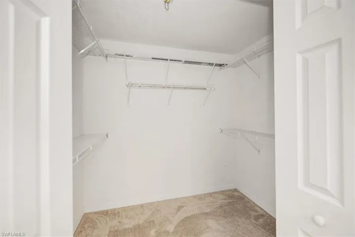 Walk-in closet featuring wire shelving, wire hanging rods, neutral wall paint, and carpet flooring