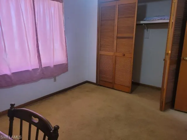 Unfurnished bedroom with light carpet and a closet