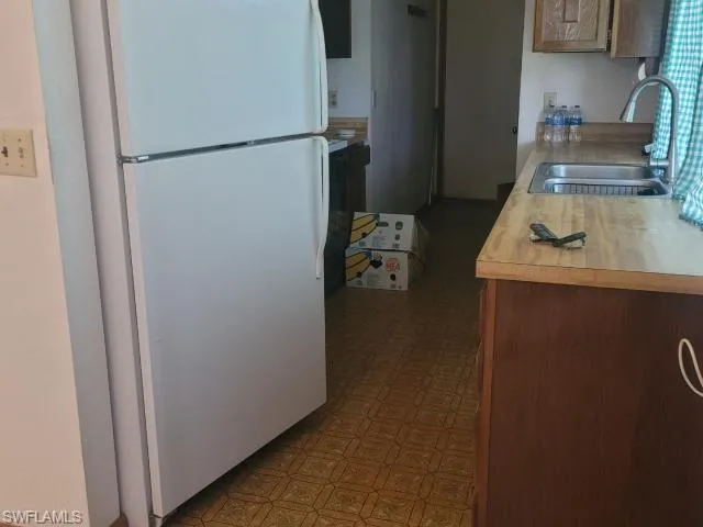 Kitchen featuring sink, white fridge, and dark tile patterned floors