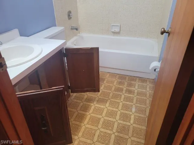 Full bathroom with vanity, tile patterned flooring, toilet, and washtub / shower combination
