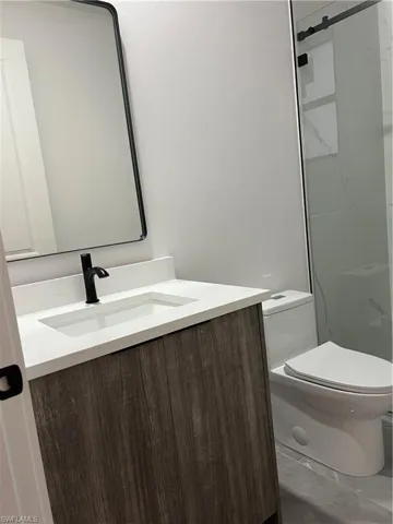 Bathroom featuring vanity and a marble finish shower