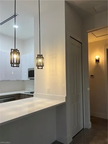 Guest house Kitchen with light countertops, white cabinetry, modern cabinets, dishwasher, and decorative light fixtures
