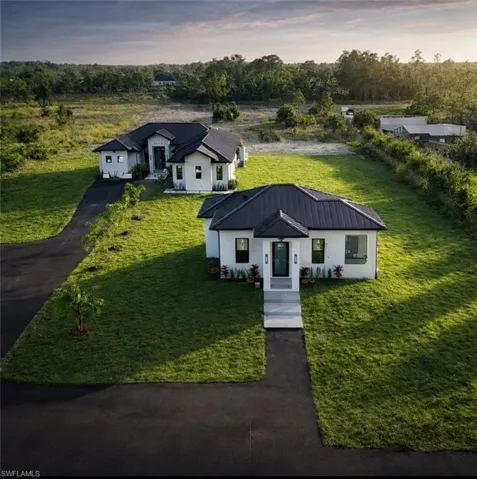 View of front facadeñ featuring a front yard, a metal roof, driveway, and stucco siding