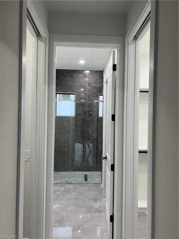 Bathroom with a stall shower, light marble finish floors, and a walk in closet