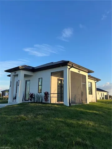 Rear view of property with a yard and stucco siding