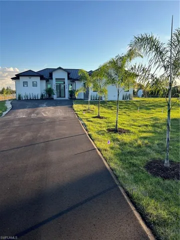 View of front of home featuring a front yard, stucco siding, and a metal roof