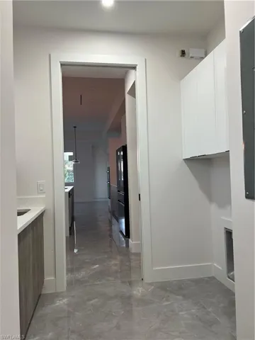 Laundry area featuring light marble finish flooring and cabinet space