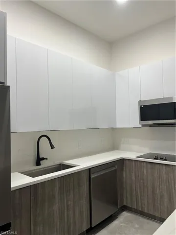 Kitchen with modern cabinets, white cabinets, dishwashing machine, and stainless steel microwave