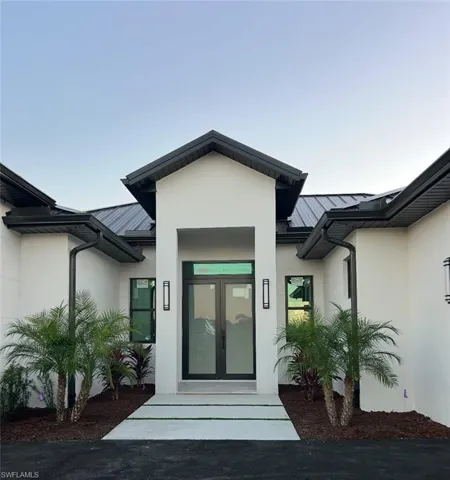 Property entrance with a metal roof, a standing seam roof, and stucco siding
