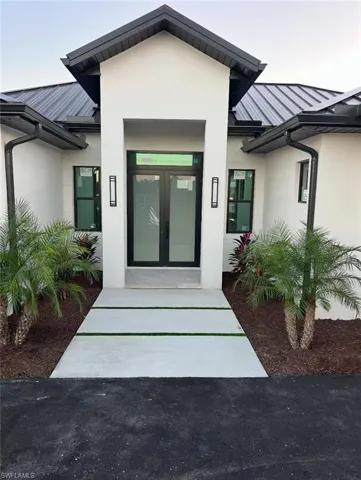 Property entrance with stucco siding, a metal roof, french doors, and a standing seam roof