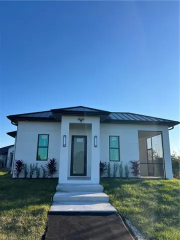 View of front facade featuring a standing seam roof, a metal roof, and a front lawn