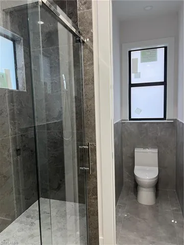 Full bathroom with a stall shower, tile walls, a wainscoted wall, and marble finish floors