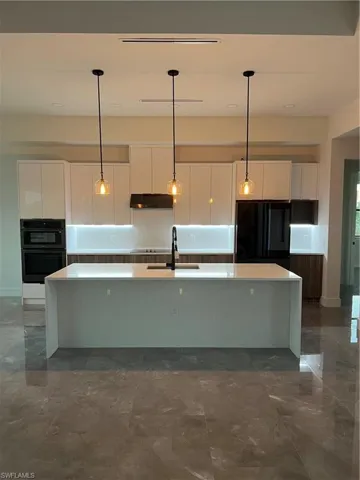Kitchen with white cabinets, a spacious island, modern cabinets, and pendant lighting