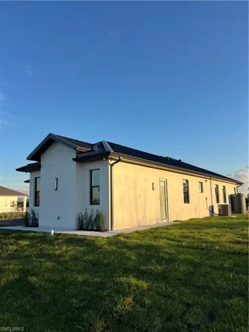 Back of property featuring a lawn and stucco siding
