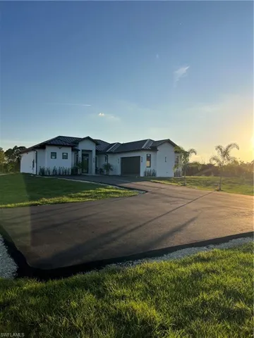 View of front of home featuring driveway, a front yard, a garage, a metal roof, and a standing seam roof