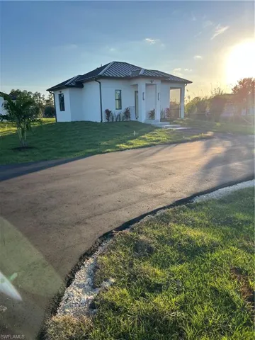 View of front facade with stucco siding, a front yard, a metal roof, and a standing seam roof