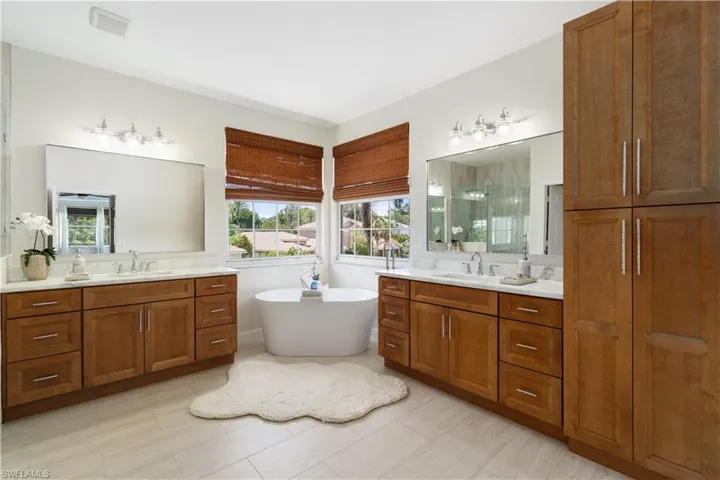 Fully remodeled primary bath is modern & open with split sinks, a modern soaking tub, and new decorative tile glass enclosed shower.