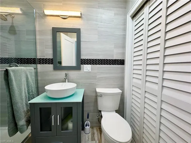 Bathroom featuring vanity, toilet, tile walls, and a shower with shower door