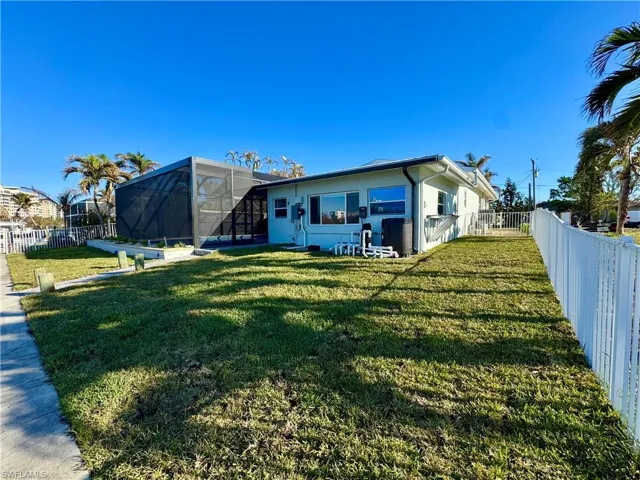 Back of house featuring glass enclosure and a yard