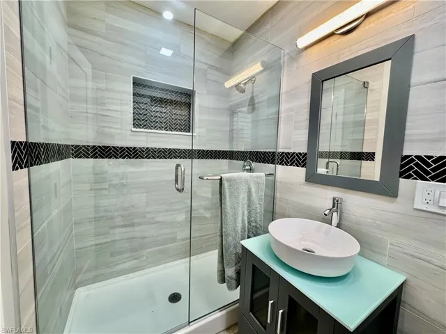 Bathroom featuring vanity, an enclosed shower, and tile walls