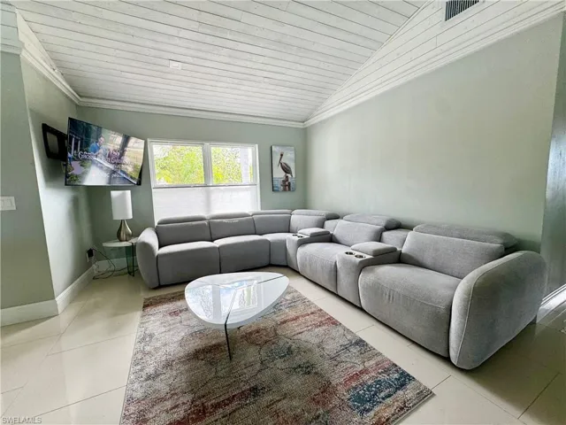Tiled living room with lofted ceiling, wood ceiling, and ornamental molding