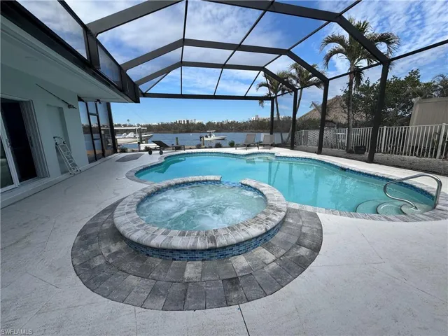 View of pool with a patio, glass enclosure, and an in ground hot tub