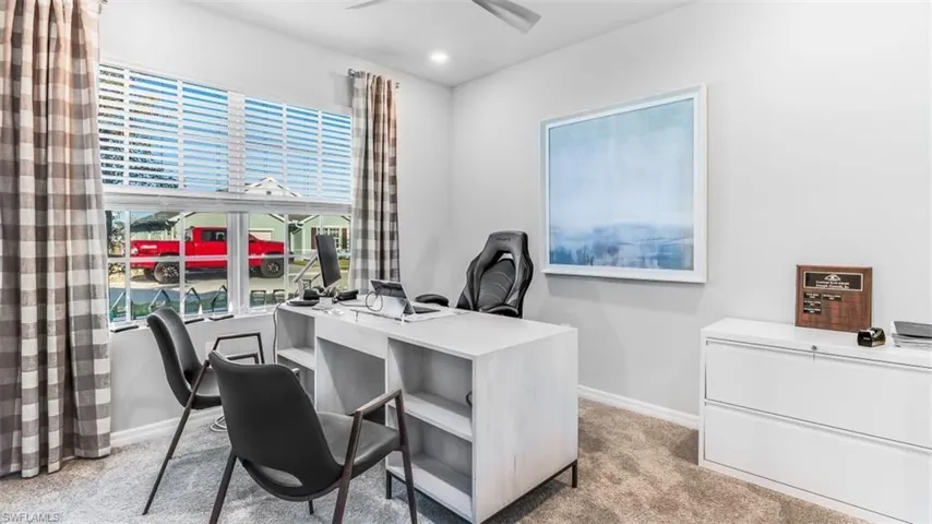 Model home. Office area with light colored carpet and a ceiling fan